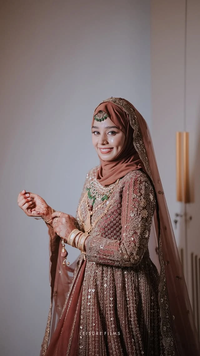 a gorgeous muslim bride with nude brown lehanga smiling to the camera , captured by the best wedding photographer in calicut