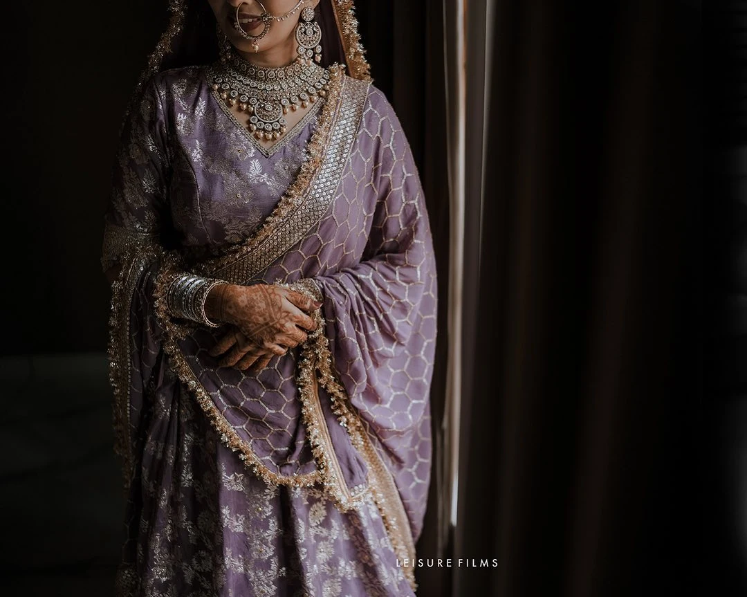 Graceful bride in lavender lehenga with intricate embroidery, silver jewelry, and mehndi, beautifully photographed by the best wedding photographer in Calicut.