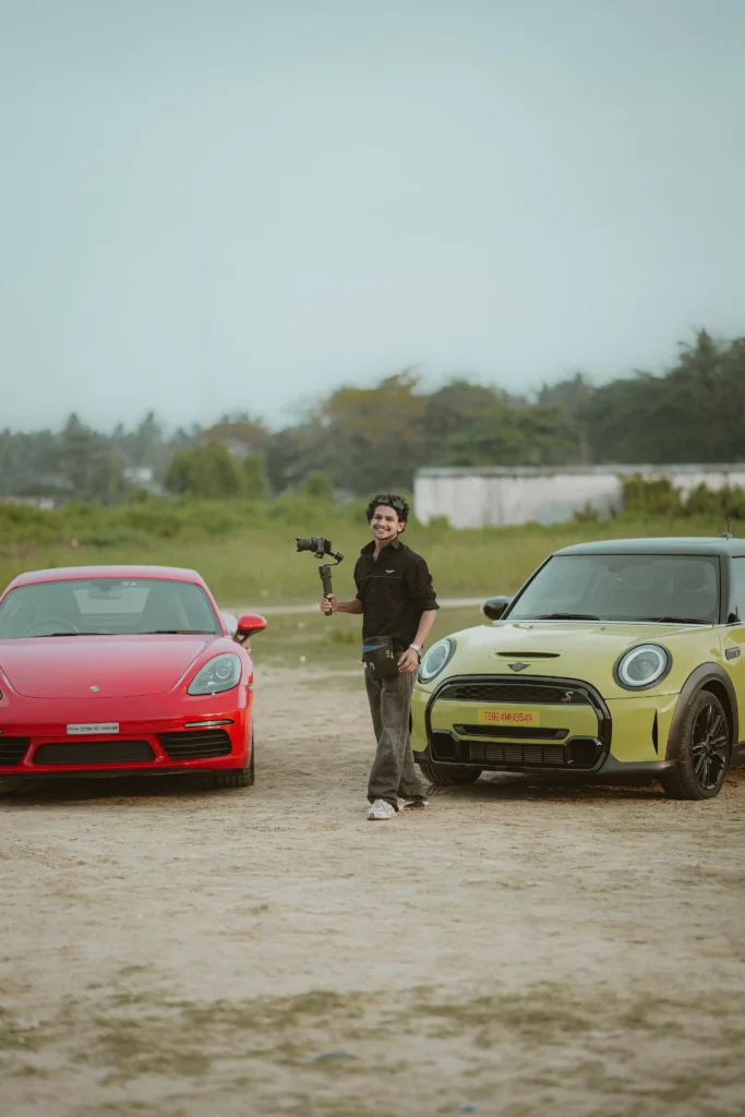 Founder of Leisure Films, the best wedding photographer in Calicut, holding a camera stabilizer between luxury cars