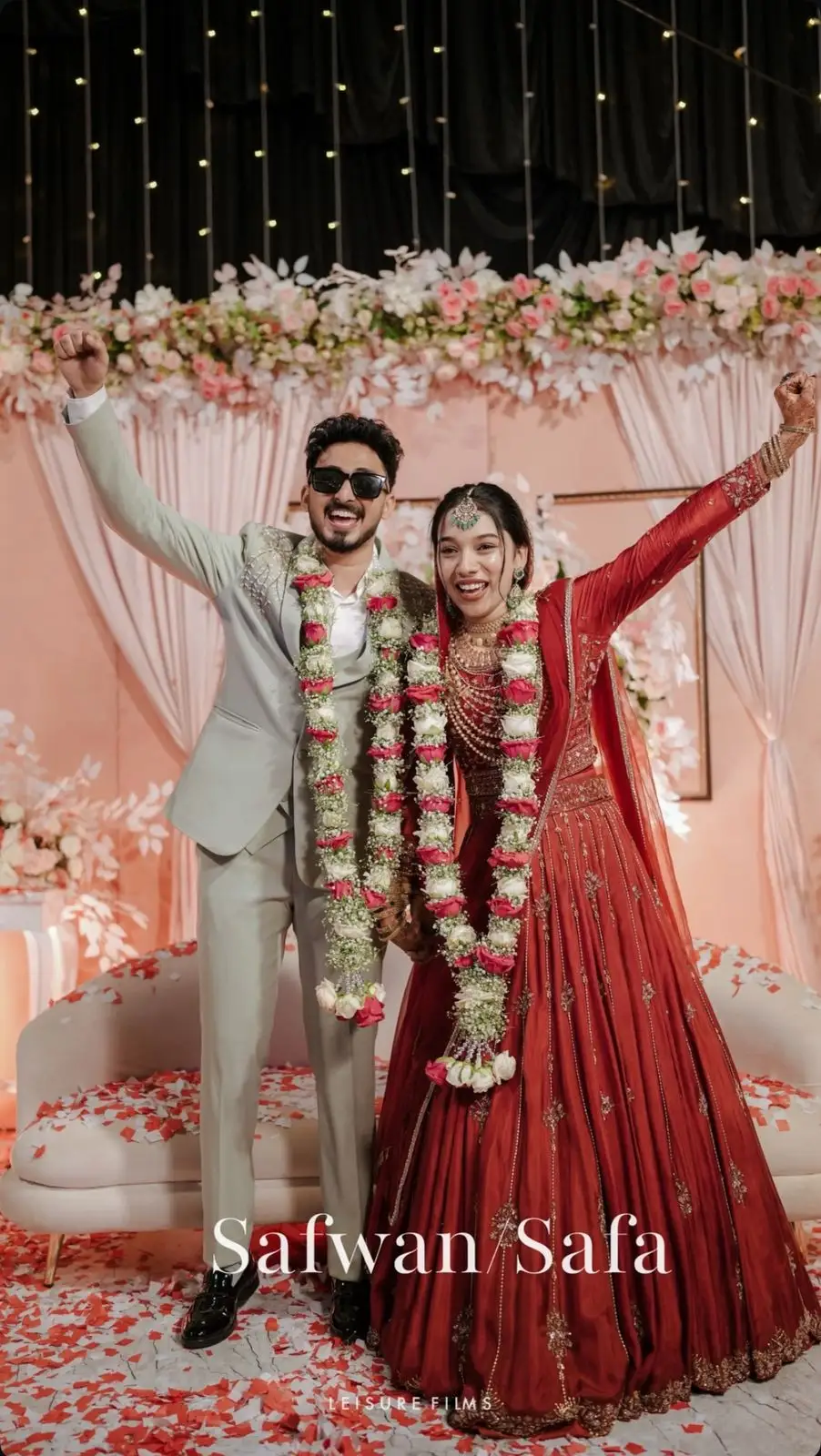 Happy wedding couple posing with garlands, captured by the best wedding photographer in Calicut.