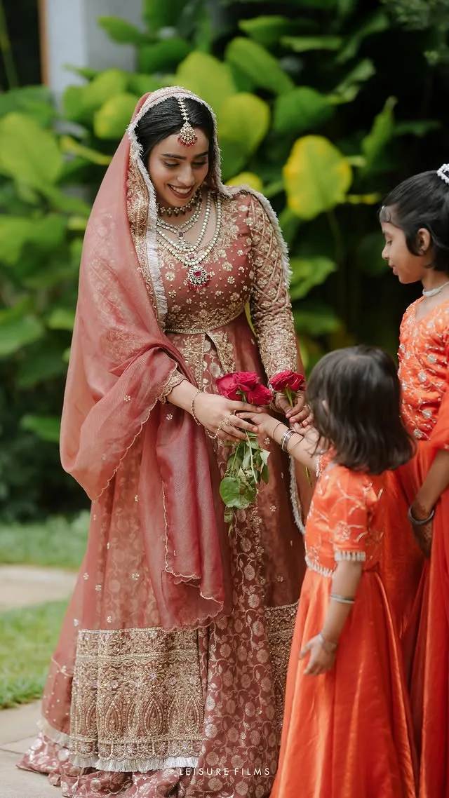 Smiling bride receiving roses from children, captured by the best wedding photographer in Calicut.